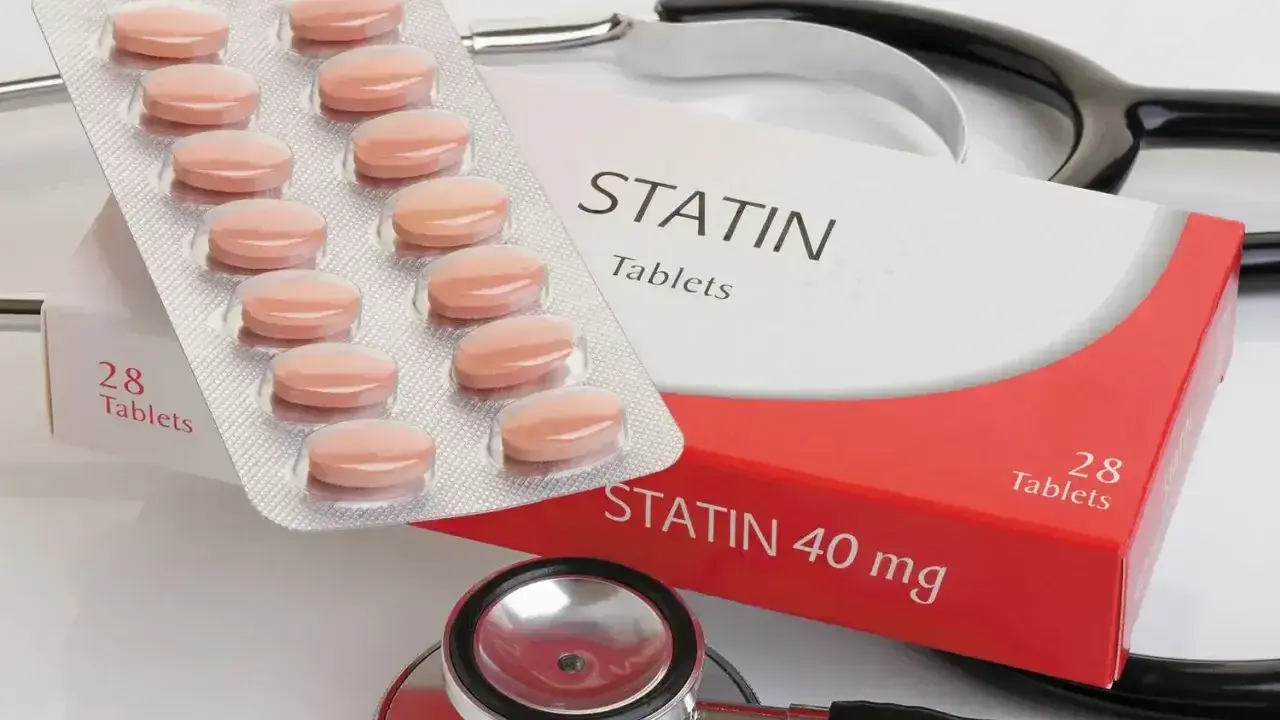 Opakowanie tabletek statynowych i blister z tabletkami. Stetoskop w tle. Statyny na co? Na obniżenie cholesterolu.