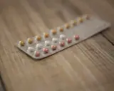 Blister opakowania tabletek antykoncepcyjnych na drewnianym tle. Zastanawiasz się nad tabletki antykoncepcyjne skutki uboczne?
