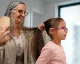 Babcia czesze wnuczkę, a jej siwe włosy przypominają o tym, dlaczego wypadają włosy.