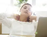 Zmęczona kobieta przy biurku masuje kark. Może potrzebuje czegoś na ból, np. Xefo Rapid na co?