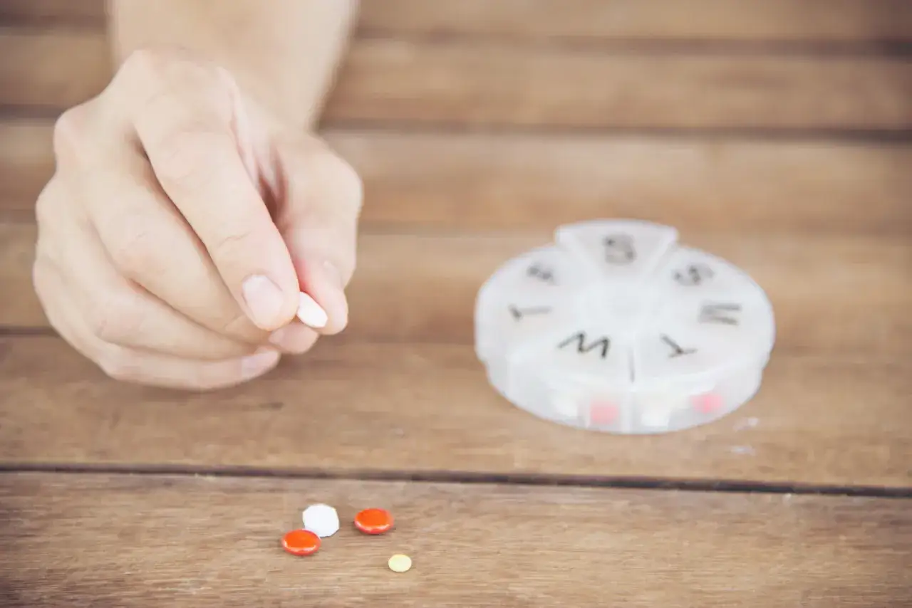 Dłoń trzyma tabletkę, obok leżą inne. Pytanie: captopril 12,5 mg jak długo działa?